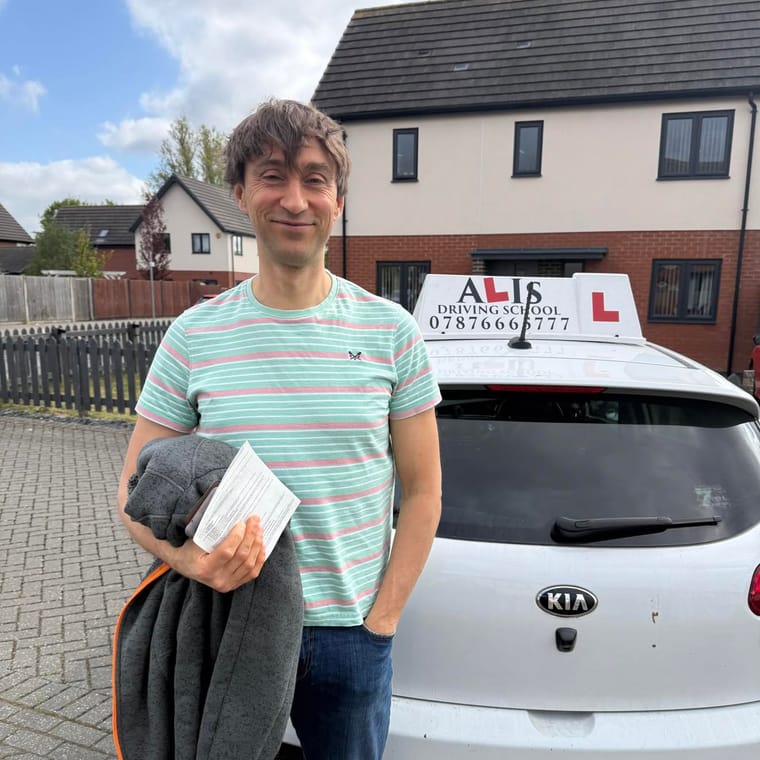 A pupil holding their practical driving test pass certificate beside Ali's car in King's Lynn.